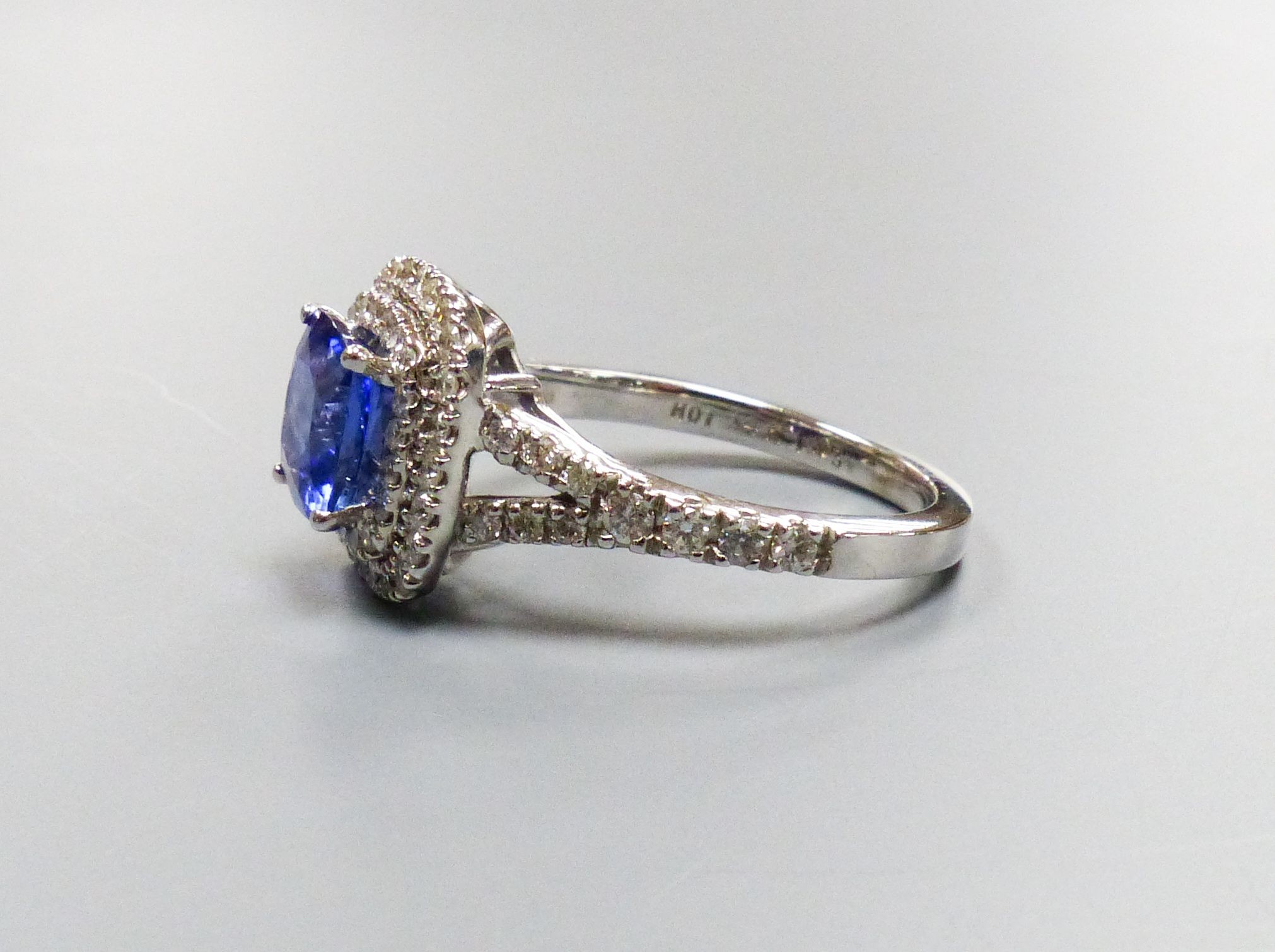 A modern 14k white metal, tanzanite and diamond set square cluster ring, with diamond set split shoulders, size M/N, gross weight 4.2 grams, the tanzanite weighing 1.63ct